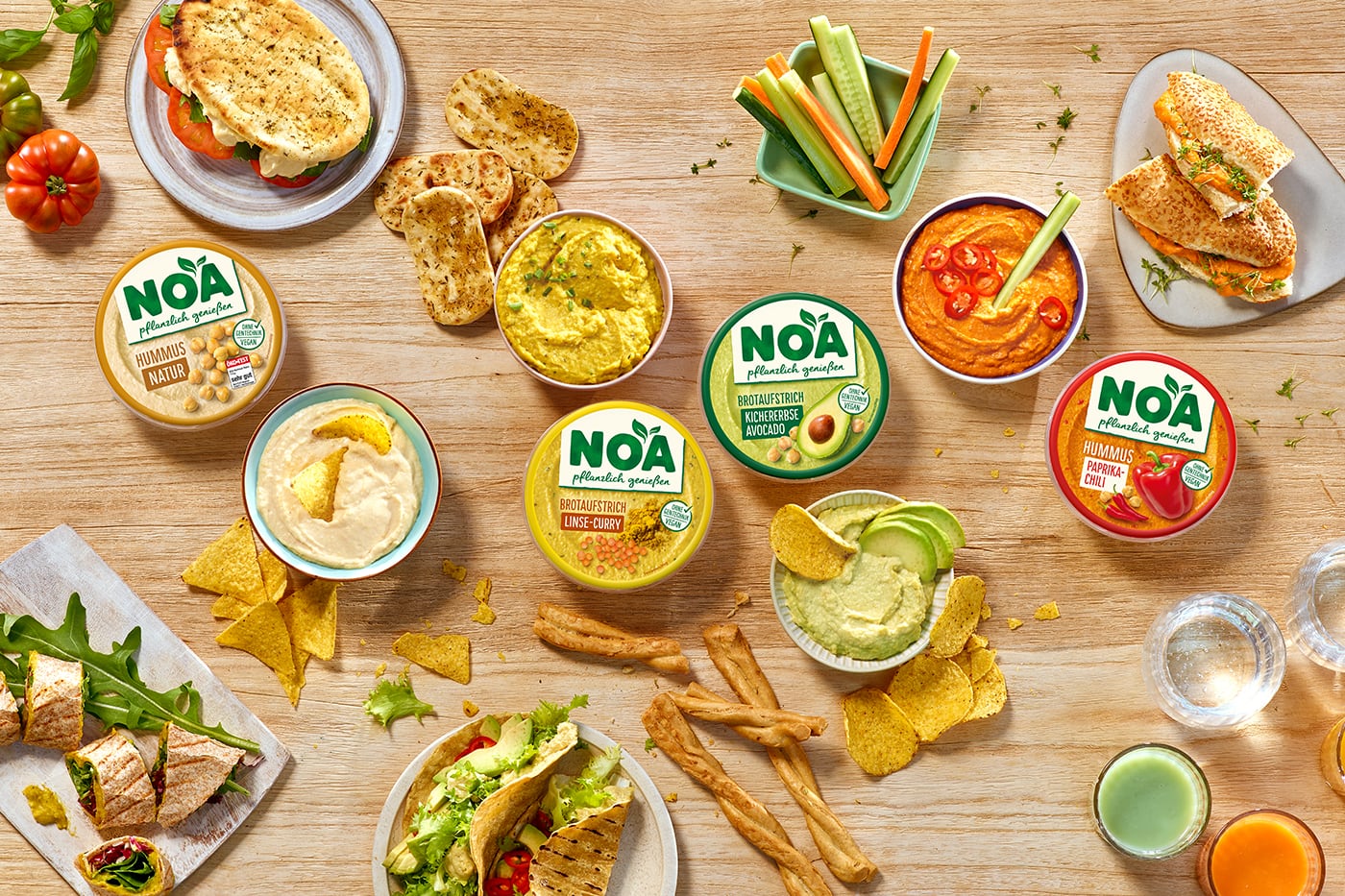 Snacktisch zeigt NOA Hummus und NOA Aufstriche, schön angerichtet mit bestrichenen Broten